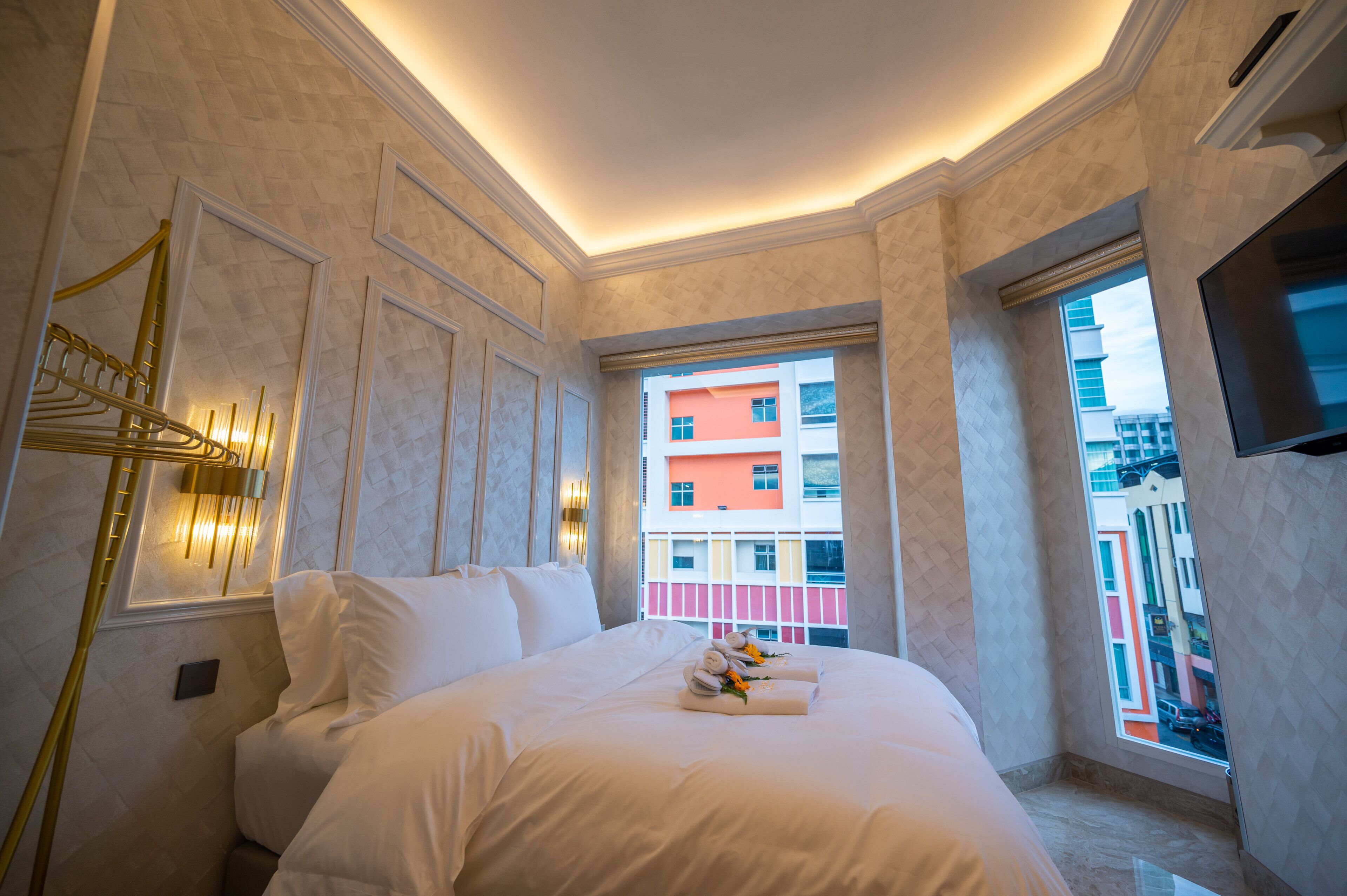 A hotel room with a large bed, a view of a colorful building, and a mounted TV on the wall.