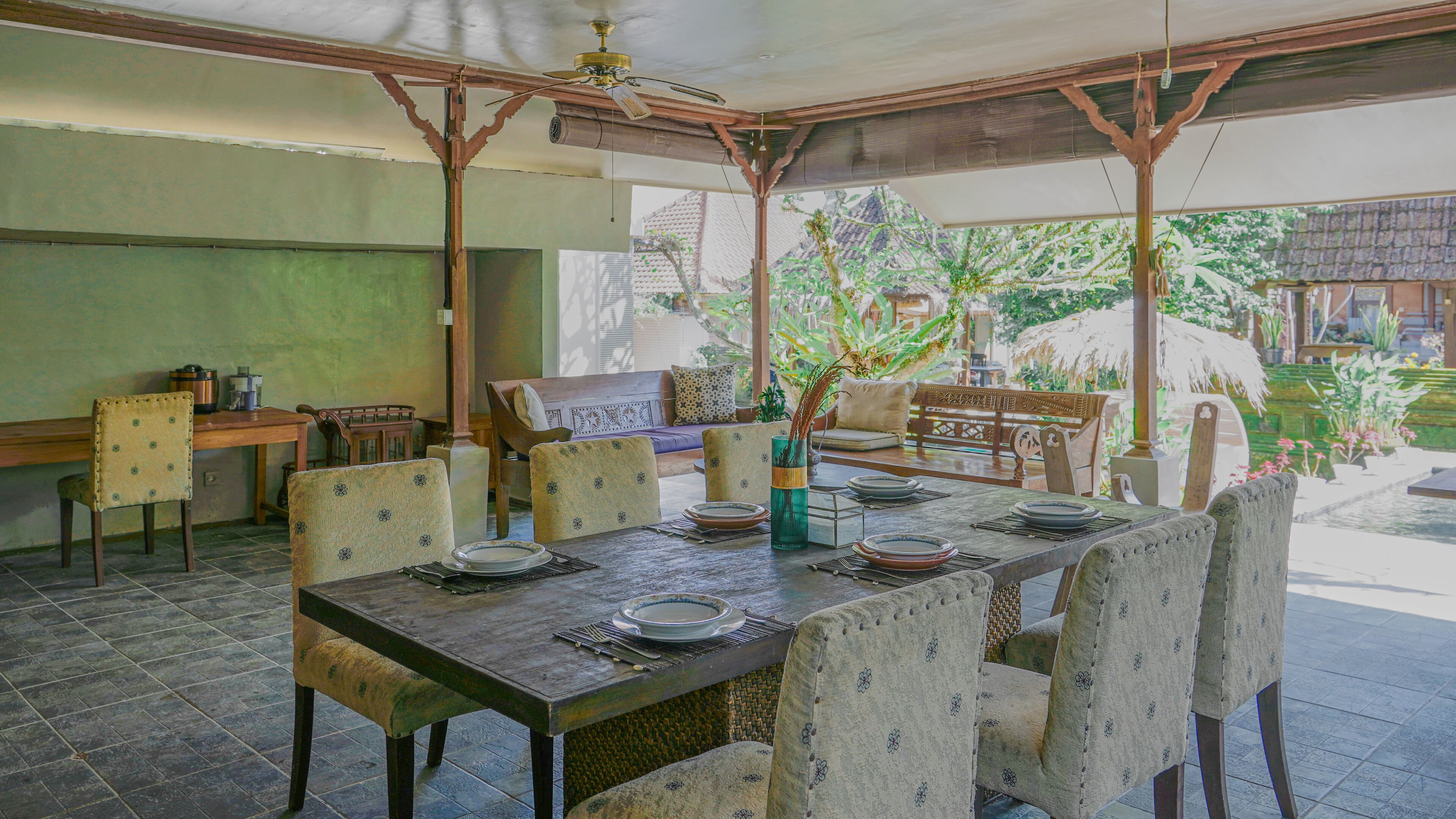 A dining area with a wooden table set for four, surrounded by patterned chairs.