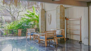 A room with a balcony, wooden furniture, a macrame wall hanging, and a tiled floor. - Lokasari Retreat (Ubud)
