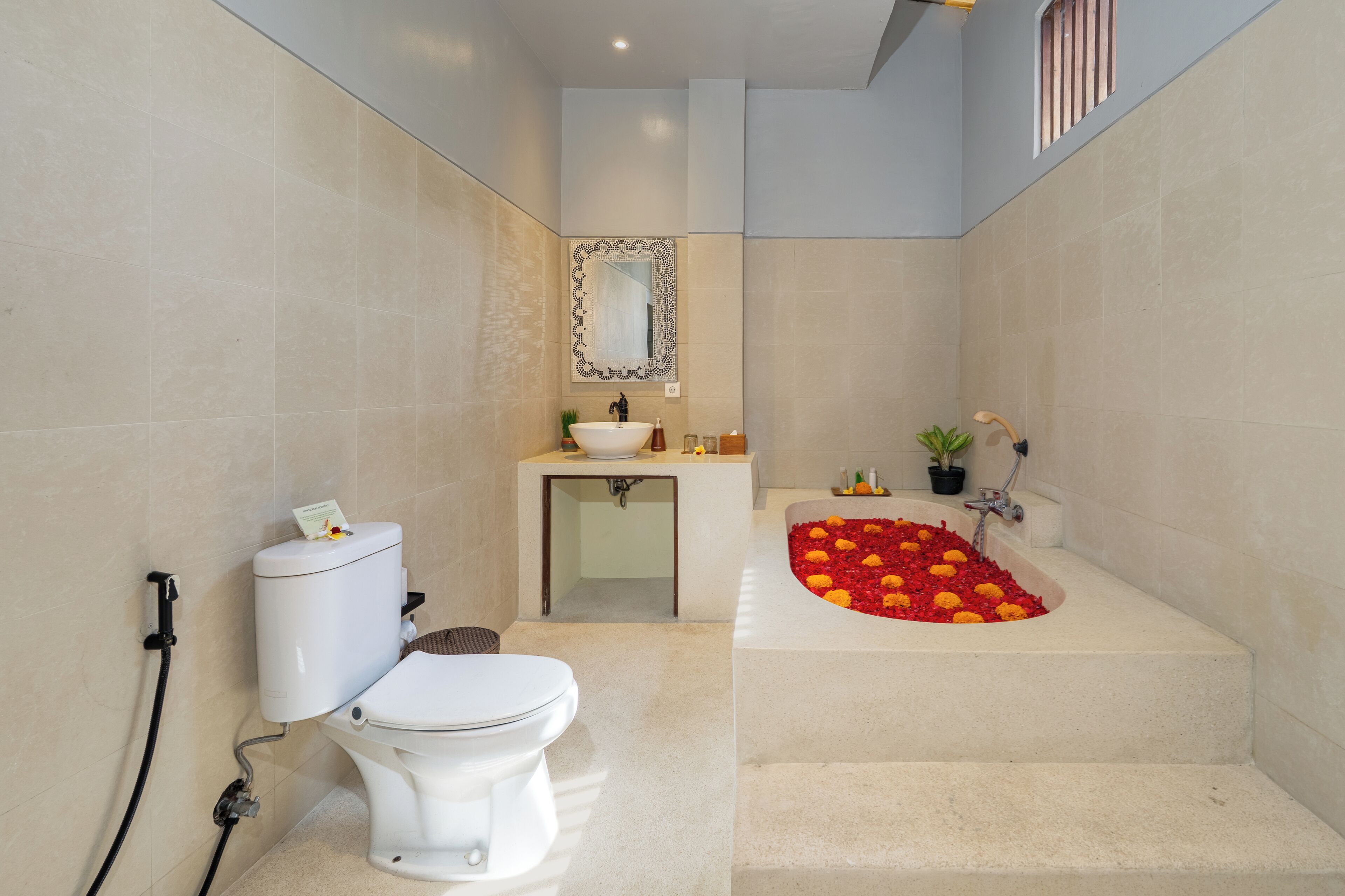 A bathroom with a toilet, sink, and bathtub with rose petals.