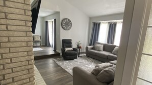 Una sala de estar moderna con chimenea, un sofá, un sillón y un televisor montado en la pared.