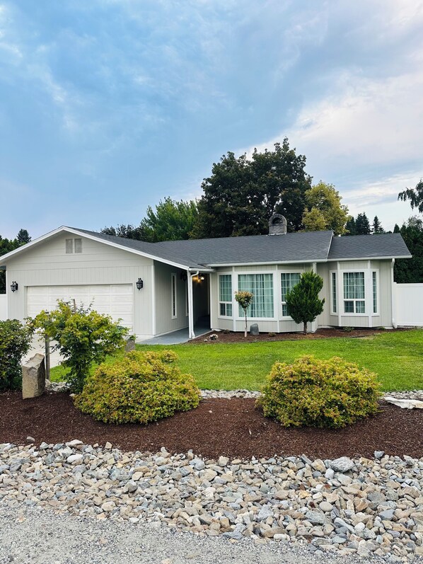 A single-story house with a garage, a covered porch, and a well-maintained lawn.