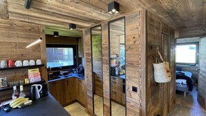 A compact kitchen with wooden walls, a built-in sink, and a window overlooking a balcony.