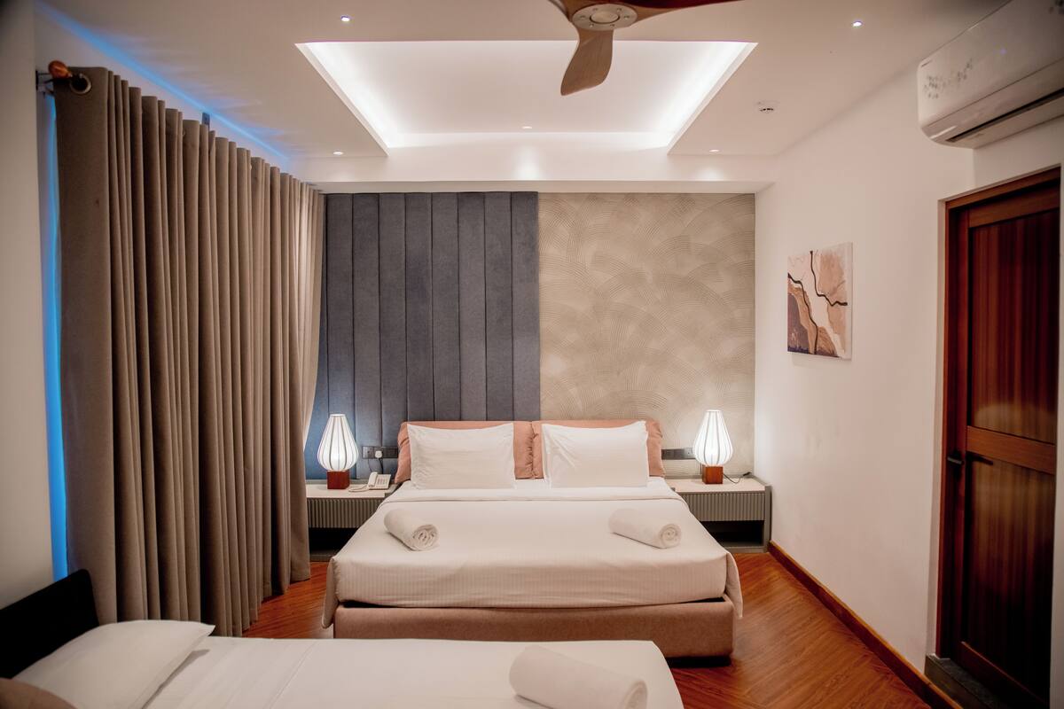 Camera d'albergo moderna con un letto grande, due comodini, una ventola a soffitto e vista sulla città.