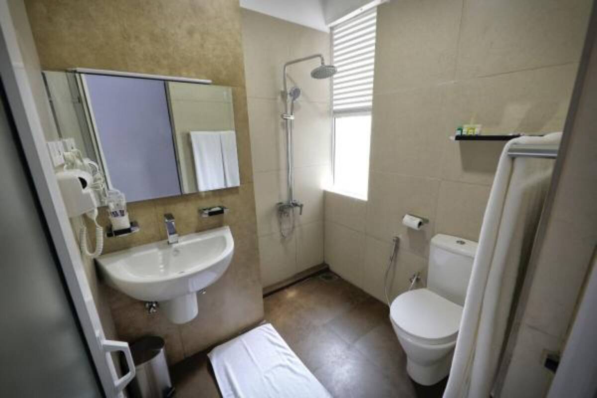 Un bagno con lavandino, specchio, servizi igienici, doccia e un asciugamano sul pavimento.