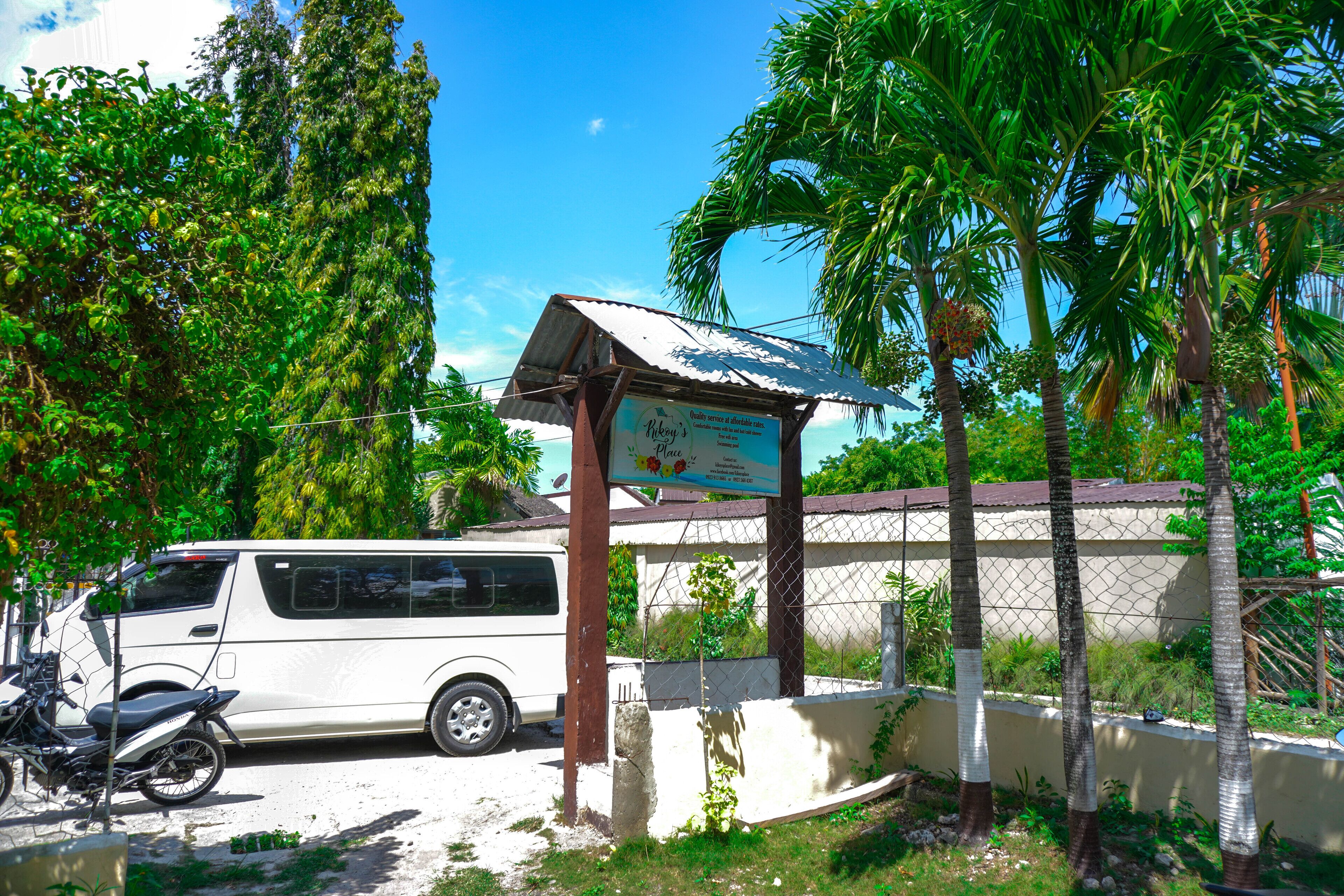 A white van parked in front of a building with a signboard.
