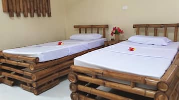 Dos camas individuales con cabeceros de madera y ropa de cama blanca, dispuestas en una habitación con suelo de baldosas.