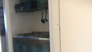 A kitchen with a gas stove, a microwave, and hanging utensils. - Belvilla by OYO SANT IRENE (Sant'Irene-torre Vecchia)