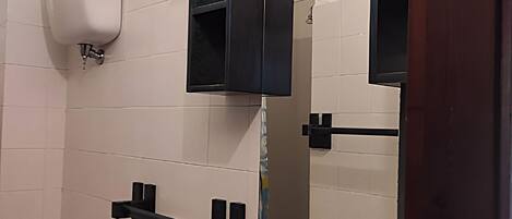 A restroom with white tiled walls, a black soap dispenser, and a mirror with a black frame.