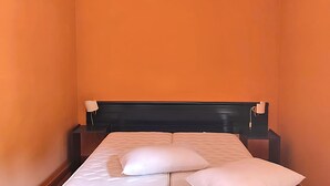 A small, single-bed room with an orange wall, a black headboard, and a white pillow on the bed. - Belvilla by OYO Appealing apartment with pool (Sant'Irene-torre Vecchia)