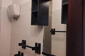 A restroom with white tiled walls, a black soap dispenser, and a mirror with a black frame. - Belvilla by OYO Appealing apartment with pool (Sant'Irene-torre Vecchia)