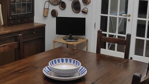Una mesa de madera para comer con un tazón y un televisor sobre un pequeño soporte.