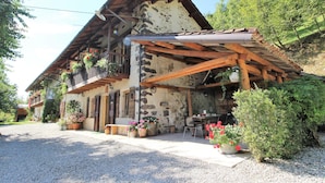 A rustic chalet with a stone facade, wooden balcony, and outdoor seating area. - Holiday Home in Feltre with Garden BBQ (Pedavena)
