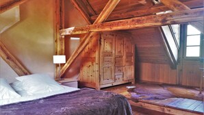 A wooden cabin bedroom with a bed, a wooden wardrobe, and a window.