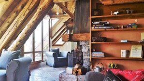 A cozy room with a sloped ceiling, a fireplace, and a bookshelf.