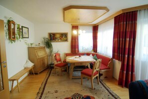 A dining area with a wooden table, red upholstered chairs, a bench, and a patterned rug.