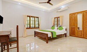 A bedroom with a bed, a desk, and a wardrobe. - Itsy Hotels Palm Grove By D2V (Kanayannur)