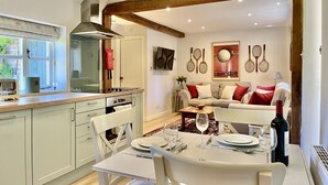 A modern kitchen with white cabinets, a built-in oven, and a window with a view of greenery. - The Old Stables by Inspire Stays dot com - a cottage that sleeps 4 guests  in 2 bedrooms (Near Petworth)