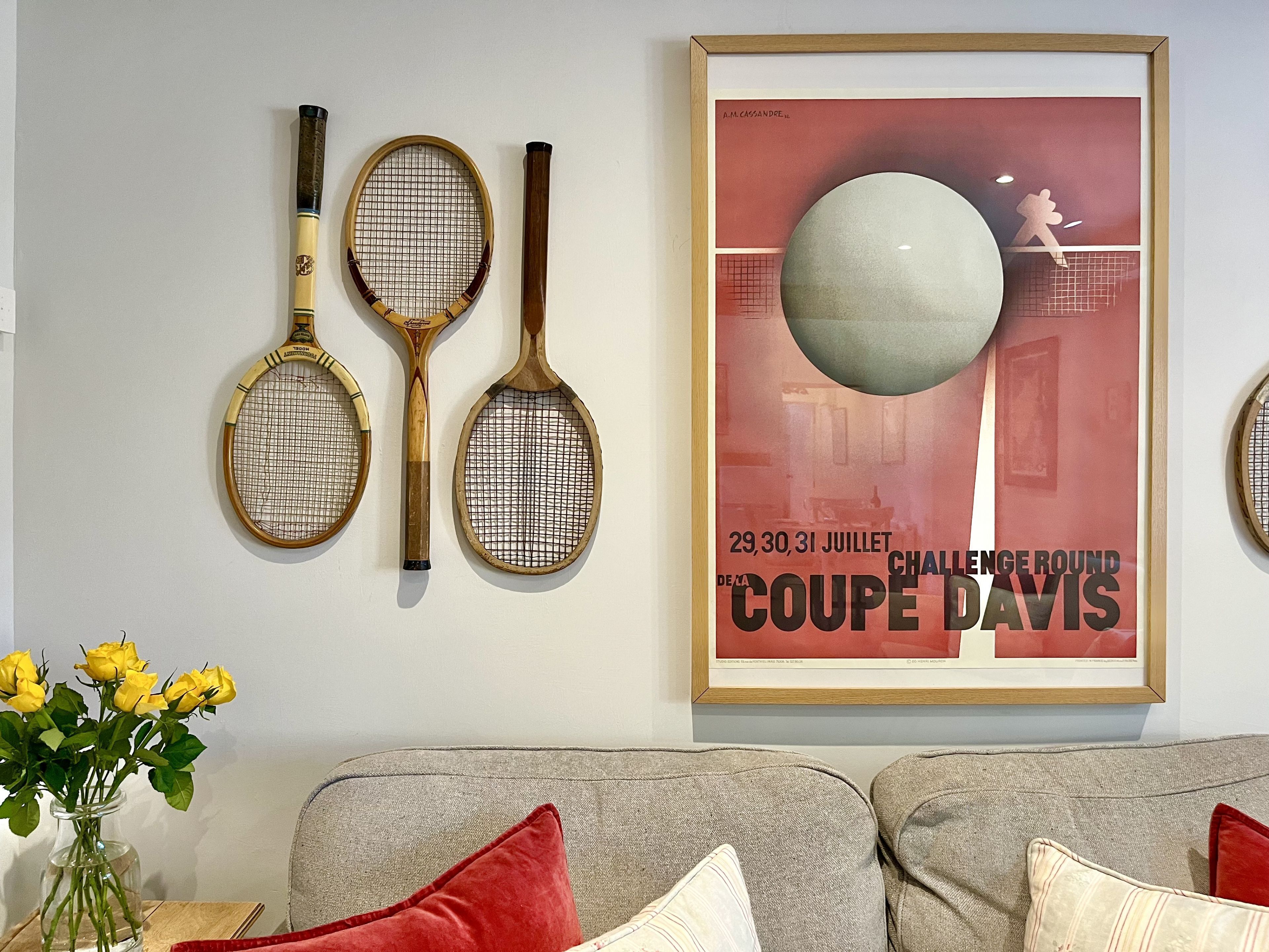 A wall with tennis rackets and a framed poster.