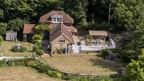 A two-story house with a fenced yard, surrounded by trees. - The Old Stables by Inspire Stays dot com - a cottage that sleeps 4 guests  in 2 bedrooms (Near Petworth)