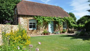 A stone house with a tiled roof, a front garden with various plants and flowers, and a wooden door. - Mill Barn by inspirestays.com - a cottage that sleeps 2 guests in 1 bedroom (North Chailey)