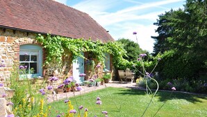 A stone house with a red-tiled roof, ivy-covered walls, and a garden with various flowers and a lawn. - Mill Barn by inspirestays.com - a cottage that sleeps 2 guests in 1 bedroom (North Chailey)