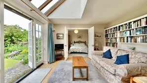 Une pièce spacieuse avec une grande fenêtre, un canapé confortable, une table basse en bois et une bibliothèque remplie de livres.