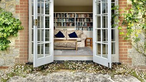 Un coin lecture confortable avec un canapé et des coussins, une bibliothèque remplie de livres et un mur en pierre.