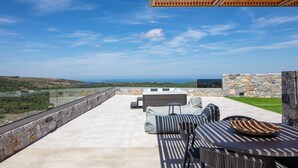 Une terrasse extérieure avec un mur en pierre, une pergola en bois et une vue sur le paysage.