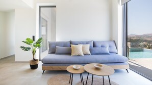 Un salon moderne avec un canapé bleu, deux petites tables rondes en bois et une plante en pot.
