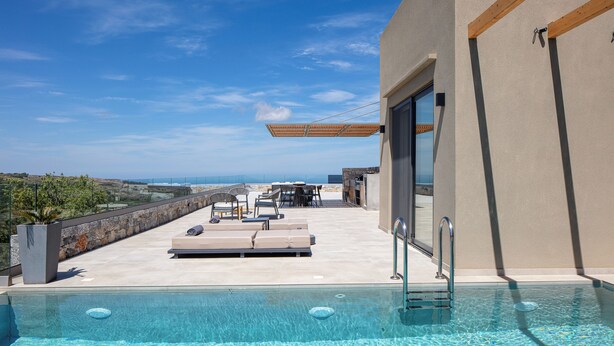 Une piscine sur le toit, dotée de chaises longues et d’une table, offrant une vue imprenable sur un paysage magnifique.