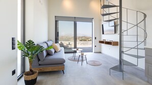 Un salon moderne avec un escalier en colimaçon, une grande fenêtre et un canapé gris.