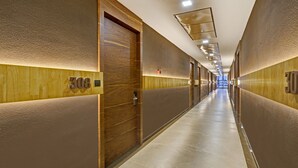 Un pasillo con paredes y puertas de madera, con los números 308 y 30, que conduce a un área luminosa y bien iluminada.
