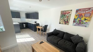A modern living room with a dark grey sofa, a wooden coffee table, and two posters on the wall. - Beautiful Private Detached 1-bed Bungalow (Penarth)