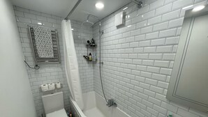 A bathroom with a white toilet, a bathtub, and a sink. - Beautiful Private Detached 1-bed Bungalow (Penarth)