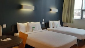A hotel room with two beds, a table, and a chair. - The Feather Factory (Long Island City)