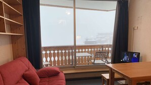 Ein gemütliches Zimmer mit einem roten Sofa, einem Holztisch und einem Fernseher.