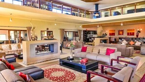 A spacious living area with multiple seating options, a central coffee table, and a decorative vase. - Kwantu Game Reserve (Gqeberha (Port Elizabeth))