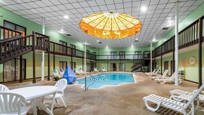 Un espace piscine int érieure doté d’un ventilateur de plafond, de chaises longues et d’un escalier.