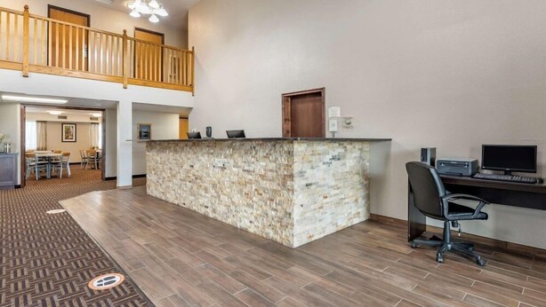 A reception area with a stone counter, a computer desk, and a dining area in the background. - Quality Inn Creston (Creston)