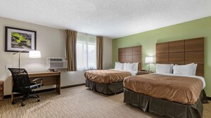 A hotel room with two beds, a desk, a chair, a window with curtains, and a framed picture on the wall. - Quality Inn Creston (Creston)