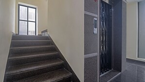 Eine Treppe aus dunklem Granit führt zu einem Aufzug in einem modernen Gebäude.