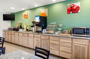 Una zona de cocina con microondas, cafetera y mostrador de alimentos.
