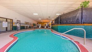 An indoor swimming pool with a tiled floor, a metal handrail, and a brick wall with a metal fence. - Baymont by Wyndham El Dorado (El Dorado)