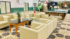 A hotel lobby with beige sofas, a pool table, and a patterned carpet. - Baymont by Wyndham El Dorado (El Dorado)