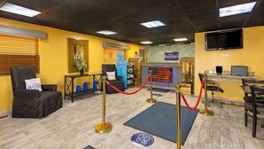 A reception area with a desk, chairs, a TV, and a red rope barrier. - Baymont by Wyndham El Dorado (El Dorado)