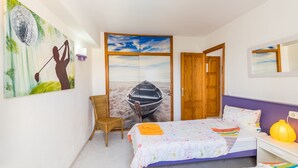 A bedroom with a bed, a chair, a painting, and a wooden door.