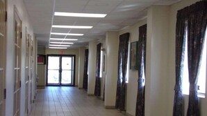 Un long couloir étroit, doté d’un sol carrelé et d’une rangée de portes d’un seul côté.