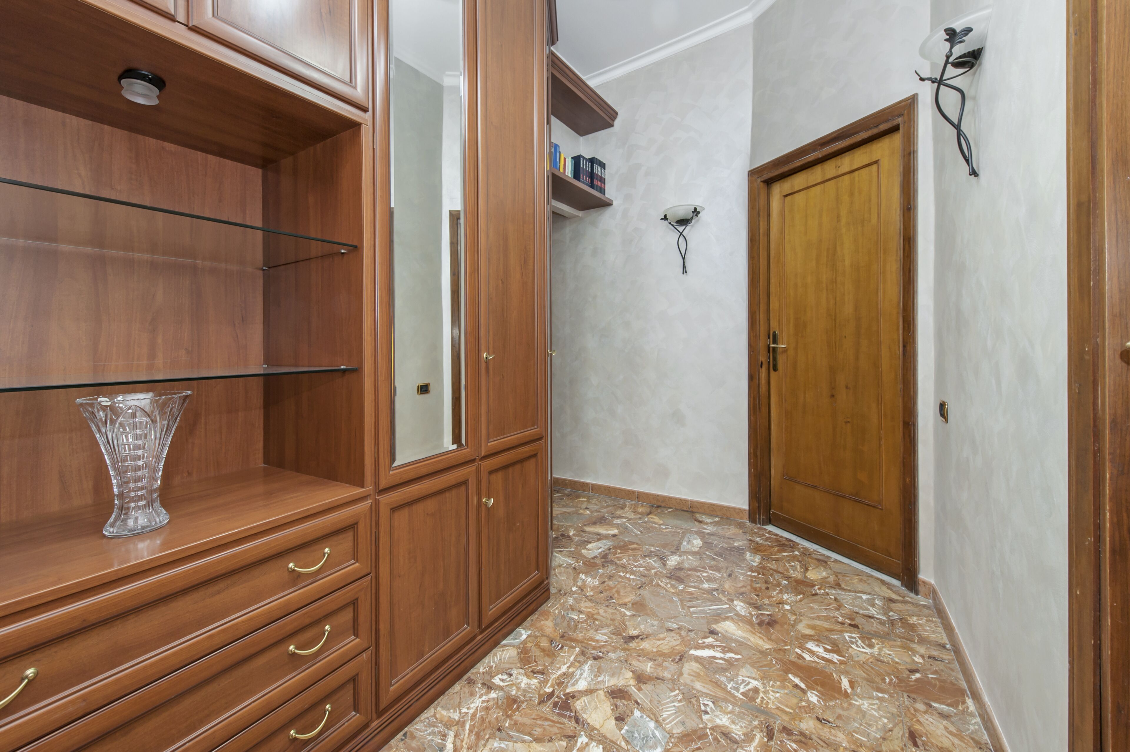 A hallway with wooden cabinets, a glass vase, and a door.