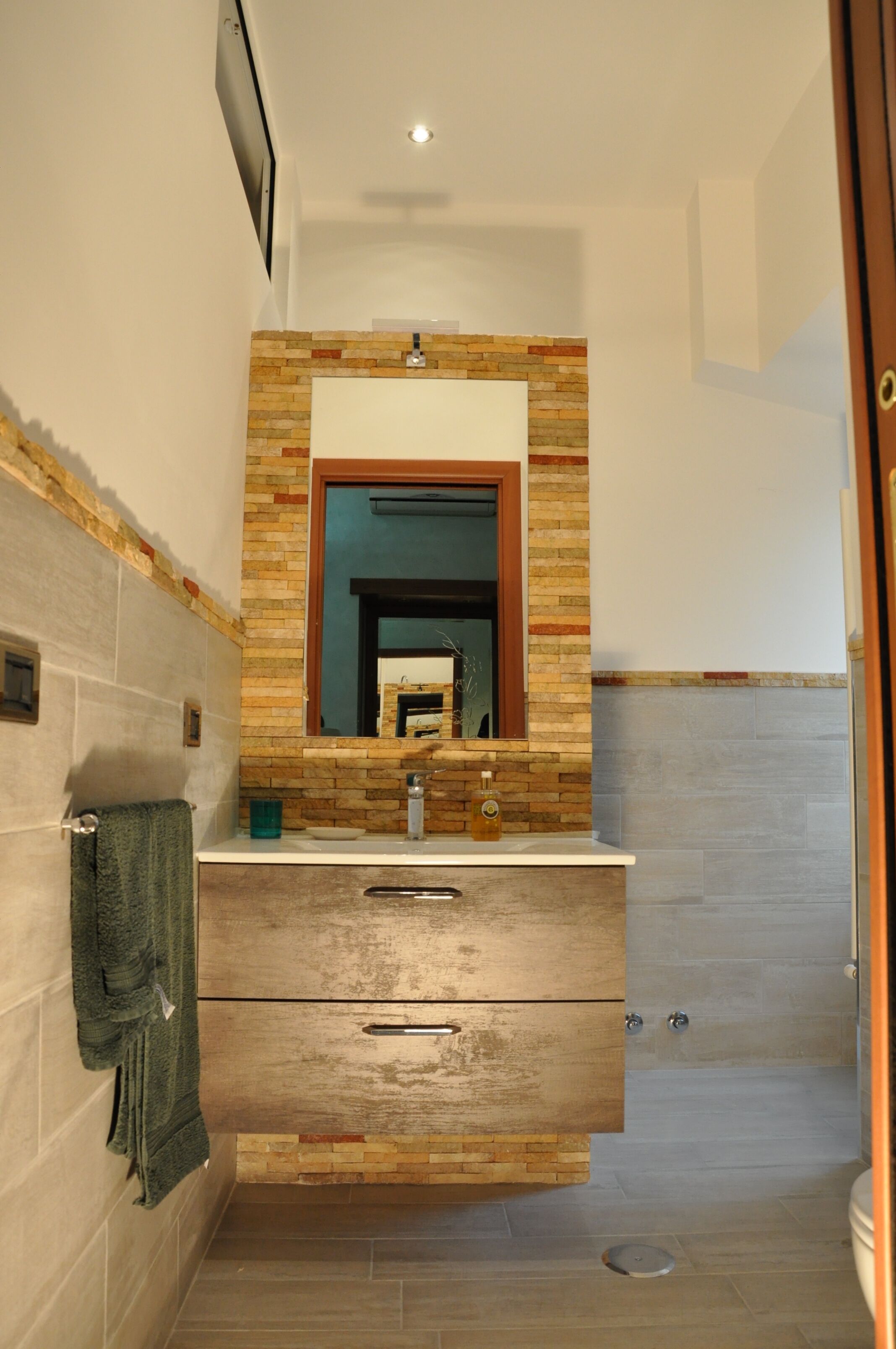 A bathroom with a wooden vanity, a mirror, and a tiled shower area.